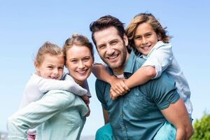 Abbildung einer vierköpfigen Familie bestehend aus Vater, Mutter, Sohn und Tochter. Die Mutter trägt die Tochter huckepack, während der Vater das selbe mit dem Sohn tut. Alle lächeln.