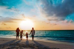 Fünfköpfige Familie, die Hand in Hand am Strand auf das Meer zu gehen und sich den Sonnenuntergang anschauen.